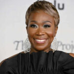 Person smiling wearing large earrings and a black top
