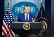 75% Budget Lock — What’s Pentagon Hiding? Man speaking at podium with flags in background
