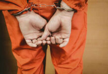 Person in orange jumpsuit with handcuffs behind back