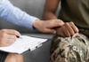 Person comforting someone in military uniform with clipboard
