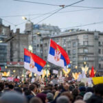 Crowd holding Serbian flags during protest in city