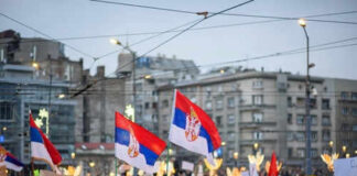 Crowd holding Serbian flags during protest in city