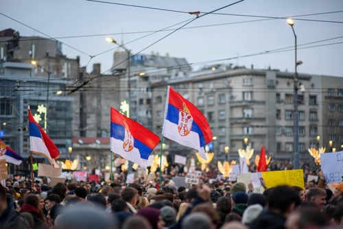 Crowd holding Serbian flags during protest in city