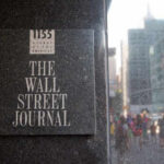 Sign for The Wall Street Journal on a building in a busy city street