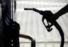 Silhouette of a hand holding a fuel nozzle at a gas station