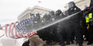 Police in riot gear spray crowd with water on government building steps