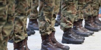 Row of soldiers in camouflage uniforms standing at attention with military boots