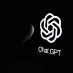 Close-up of a hand reaching towards the ChatGPT logo on a smartphone screen