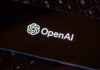Close-up of a smartphone displaying the OpenAI logo on a dark screen