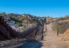 Border Wall Progress, but 2027 Deadline Remains Fluid A border wall with barbed wire in a rural landscape