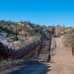 Border Wall Progress, but 2027 Deadline Remains Fluid A border wall with barbed wire in a rural landscape