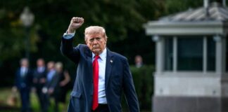 A political figure raising a fist while walking outdoors