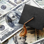 Has Washington Made Graduate School Harder To Afford? A graduation cap placed on a pile of U.S. dollar bills