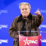 Bannon’s War Room Surges — Why Now? Person speaking at CPAC conference blue background