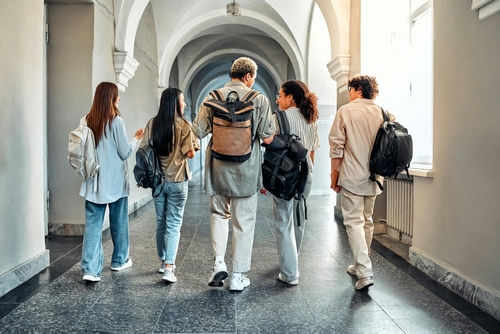 university-student2507996211 Five students walking in a school hallway together