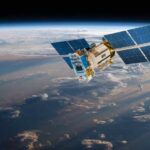 America Builds Next Generation Missile Shield A satellite equipped with solar panels orbiting above the Earth, surrounded by clouds