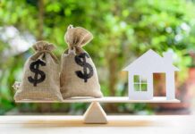 Homeownership Keeps Moving Out Of Reach Money bags and house cutout on a balance scale
