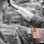 Two Fallen Troops, One Conservative Divide Soldier saluting with an American flag patch on sleeve