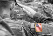 Two Fallen Troops, One Conservative Divide Soldier saluting with an American flag patch on sleeve