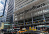 The New York Times building with traffic and yellow cabs in front