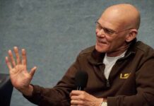 Bald man speaking into a handheld microphone