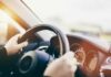 Hands gripping a steering wheel inside a car