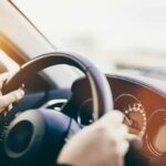 Hands gripping a steering wheel inside a car
