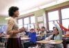 The Next Education Battle Starts With Climate Teacher engaging with students raising hands in a classroom
