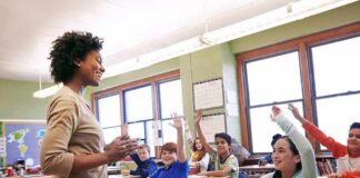Teacher engaging with students raising hands in a classroom
