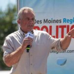 Washington’s Vaccine Debate Isn’t Going Away Man speaking on an outdoor stage with a microphone