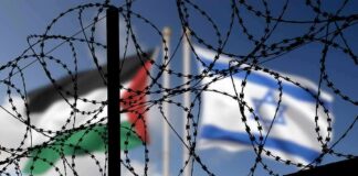 Barbed wire coils with blurred Palestinian and Israeli flags in background