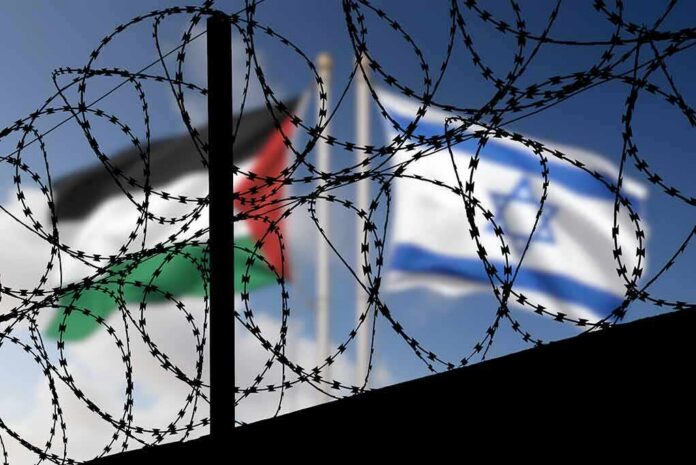 shutterstock_2373852943 Barbed wire coils with blurred Palestinian and Israeli flags in background