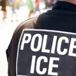 After Fatal Encounters, ICE Changes Course Close-up of a police officer's back with a 'POLICE ICE' badge
