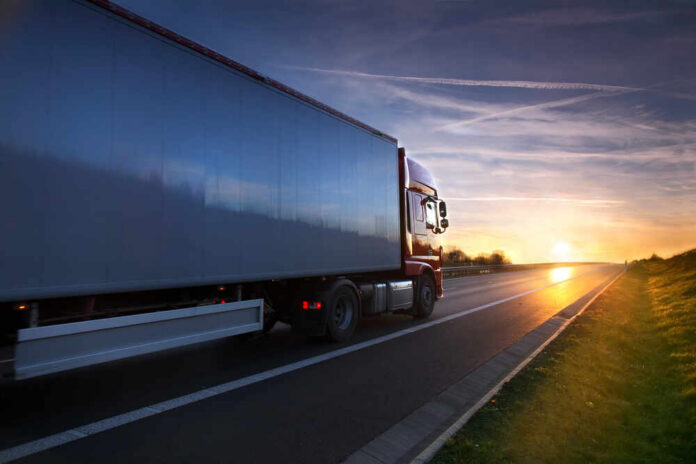 Truck,Transportation,On,The,Road,At,Sunset A truck driving on a highway during sunset