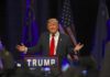 Trump’s Collins Joke Sparked a New Culture Clash speaker at podium with flags addressing audience