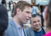 Warrant Drop at SFO — Swalwell Devices Seized Man in a gray blazer speaking at an outdoor event