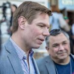 Warrant Drop at SFO — Swalwell Devices Seized Man in a gray blazer speaking at an outdoor event