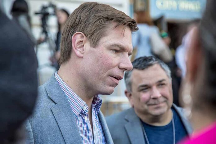 Man in a gray blazer speaking at an outdoor event