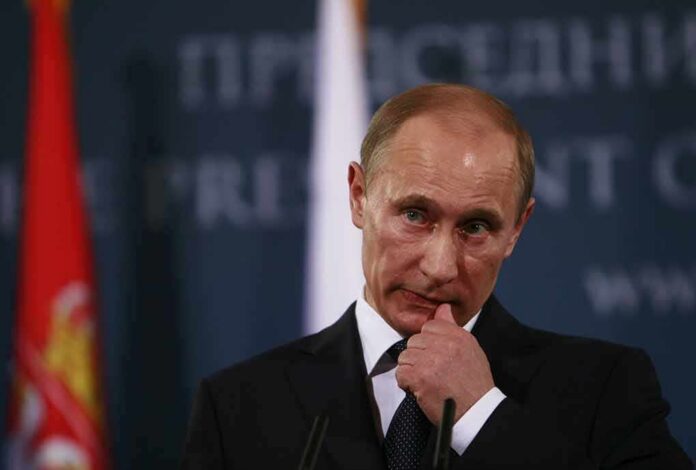 man in suit at podium touching his face
