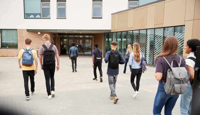 shutterstock_1188882382 Students with backpacks walking toward a school entrance