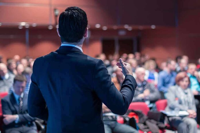 shutterstock_1349356253 Speaker addressing an audience in a conference hall