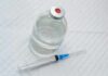 Doctors Sound Alarm—Access Still Expands Vial of clear liquid with syringe on a white surface