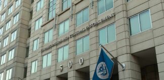 U.S. government building facade with American and blue departmental flags