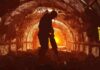 Miner silhouette using a jackhammer in a dimly lit tunnel