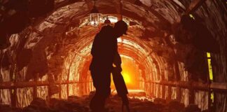 Miner silhouette using a jackhammer in a dimly lit tunnel
