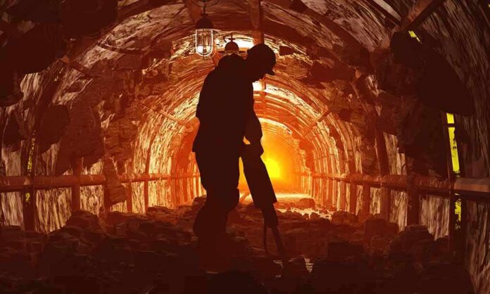 shutterstock_176428352 Miner silhouette using a jackhammer in a dimly lit tunnel