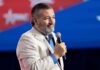 Cruz Calls for Arming Iran’s Protesters Now Man in light blazer holding a microphone on stage