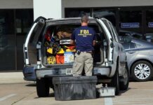 FBI evidence technician working at the open back of an SUV
