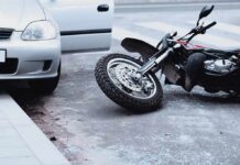 Motorcycle lying on the street beside a car with an open door