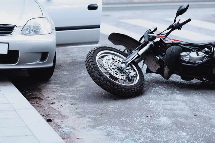 Motorcycle lying on the street beside a car with an open door